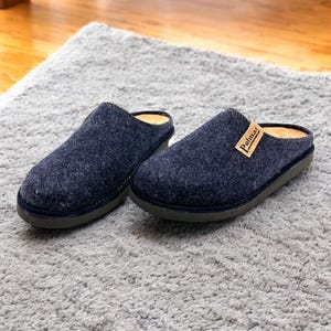 Puede incluir: Un par de zapatillas de lana azul oscuro con suela de cuero marr&oacute;n. Las zapatillas tienen un dise&ntilde;o sencillo y est&aacute;n etiquetadas con "Polmar" en la parte superior de una zapatilla.