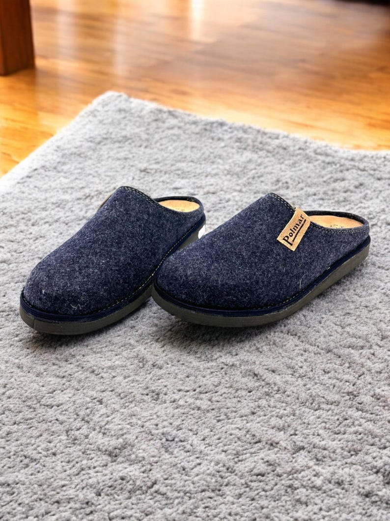 Puede incluir: Un par de zapatillas de lana azul oscuro con suela de cuero marr&oacute;n. Las zapatillas tienen un dise&ntilde;o sencillo y est&aacute;n etiquetadas con "Polmar" en la parte superior de una zapatilla.