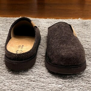 Puede incluir: Un par de zapatillas de fieltro marr&oacute;n con suela de goma negra. Las zapatillas tienen un forro de fieltro marr&oacute;n y una parte superior de fieltro marr&oacute;n.