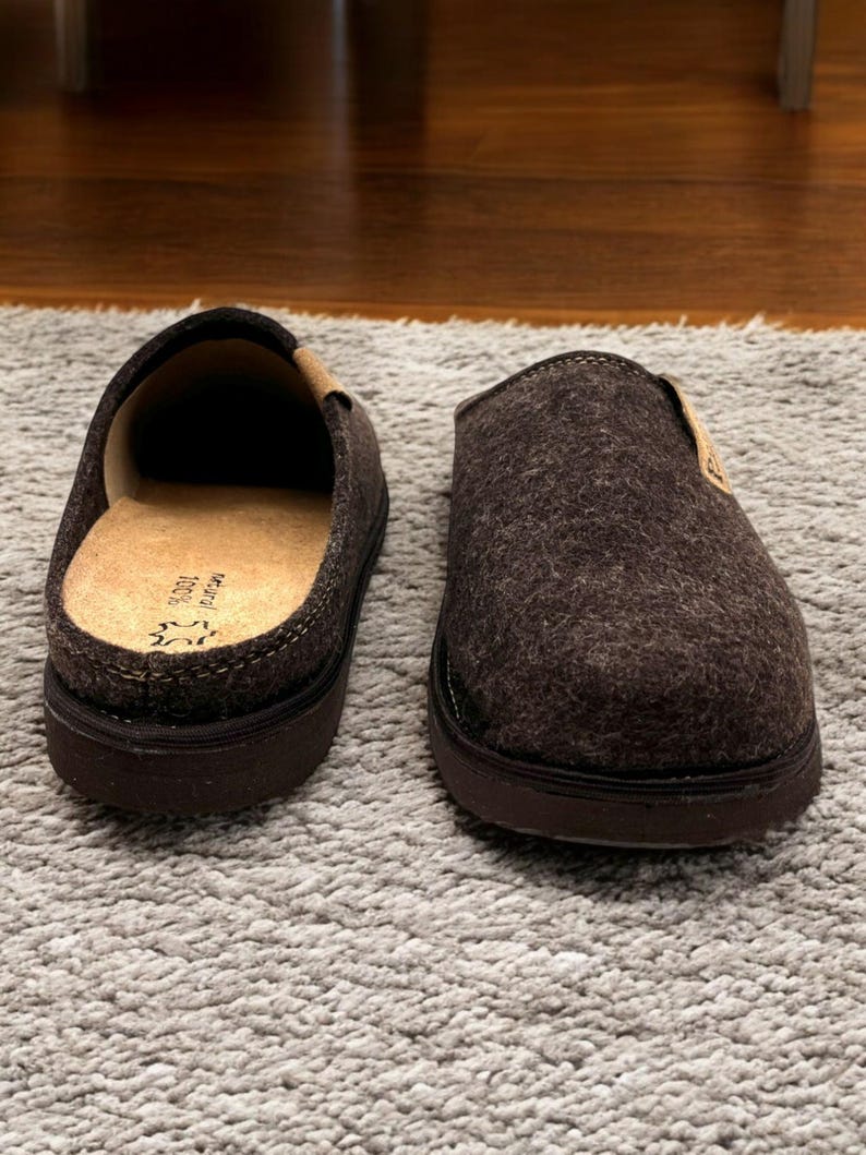 Puede incluir: Un par de zapatillas de fieltro marr&oacute;n con suela de goma negra. Las zapatillas tienen un forro de fieltro marr&oacute;n y una parte superior de fieltro marr&oacute;n.