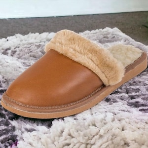 Könnte beinhalten: Ein brauner Lederschlappen mit einem Kunstfellbesatz. Der Schlappen hat eine geschlossene Spitze und eine leicht abgerundete Form.