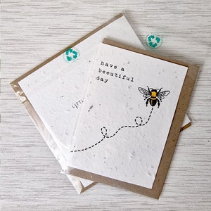 May include: A white card with a bee and the text "have a beautiful day" printed on it. The card is wrapped in a brown envelope and sealed with a clear plastic sleeve.