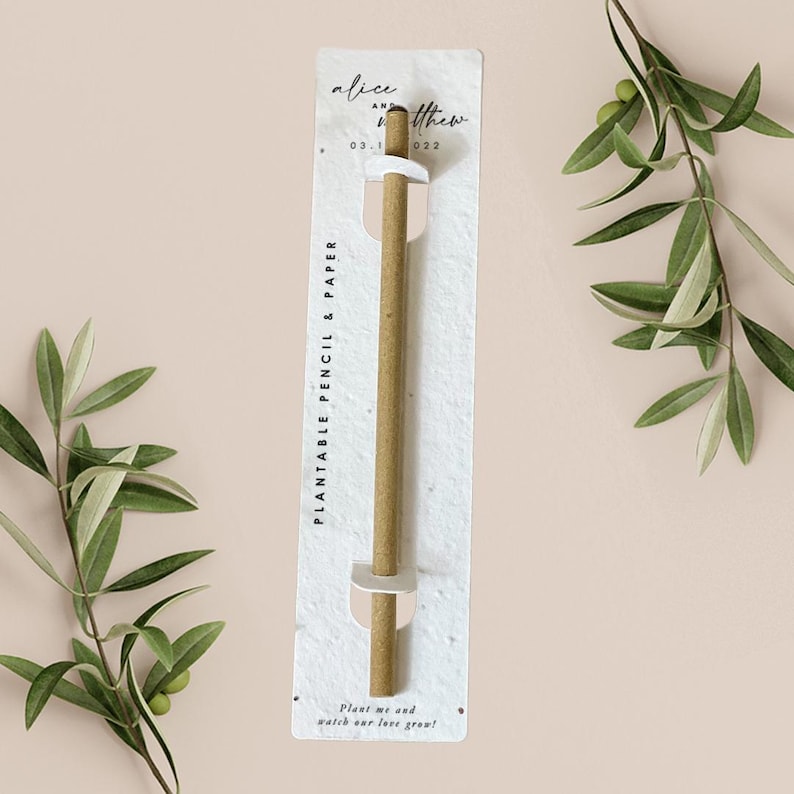 Puede incluir: Una tarjeta blanca con texto negro que dice "Plantable Pencil & Paper" y "&iexcl;Pl&aacute;nteme y observe c&oacute;mo crece nuestro amor!" La tarjeta tiene un agujero en el medio y un l&aacute;piz marr&oacute;n sobresale del agujero. El texto "alice and matthew 03.1.022" est&aacute; en la parte superior de la tarjeta.