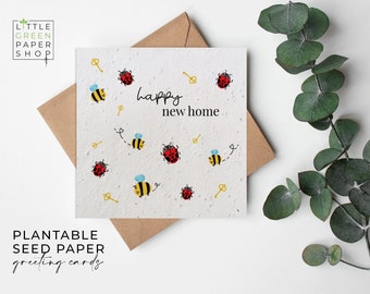 May include: Plantable seed paper greeting card with a white background and a brown envelope. The card features a colorful illustration of ladybugs and bees with the text "happy new home".
