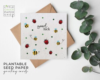 May include: A white seed paper greeting card with a green shamrock and ladybug pattern. The card says "good luck" in black text.