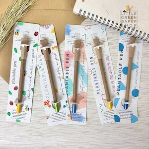 May include: Five colorful cards with a brown, plantable pen on each. The cards have a watercolor background and the text "Plantable Pen" and "Plant me and watch me grow!" printed on them. The pens have a seed capsule at the end that can be planted to grow flowers.