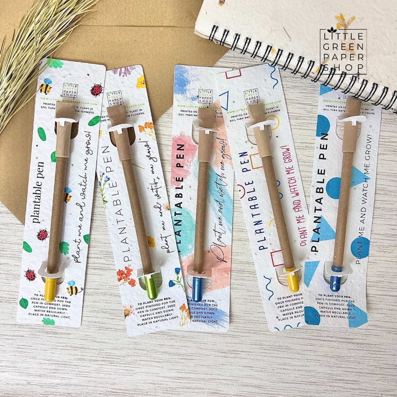 May include: Five colorful cards with a brown, plantable pen on each. The cards have a watercolor background and the text "Plantable Pen" and "Plant me and watch me grow!" printed on them. The pens have a seed capsule at the end that can be planted to grow flowers.