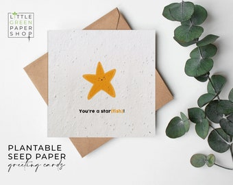 Può includere: Un biglietto d'auguri in carta da seme plantabile bianca con un'illustrazione di stella marina gialla e il testo "You're a star(fish)!".