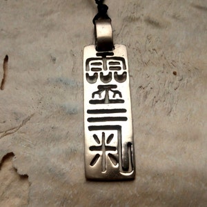 Può includere: Collana con ciondolo in argento con un ciondolo rettangolare che presenta un design stilizzato di caratteri cinesi.