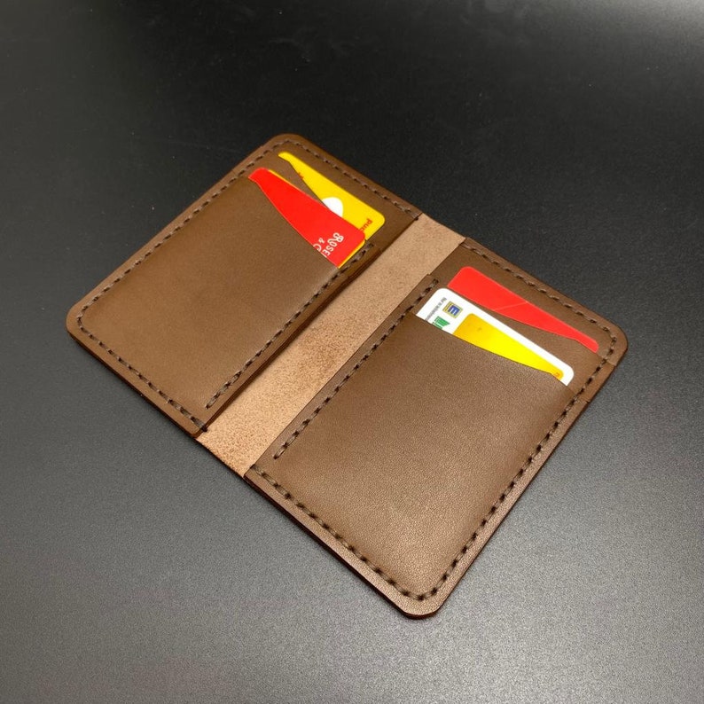 May include: A brown leather wallet with two card slots. The wallet is closed and has a stitched edge.