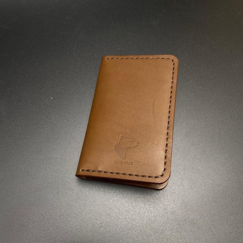 May include: A brown leather wallet with a bear silhouette and the text "HANDMADE" embossed on the front.
