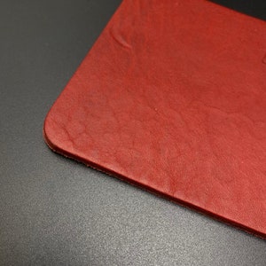 May include: A close-up of a red leather surface. The leather has a textured, grainy appearance.