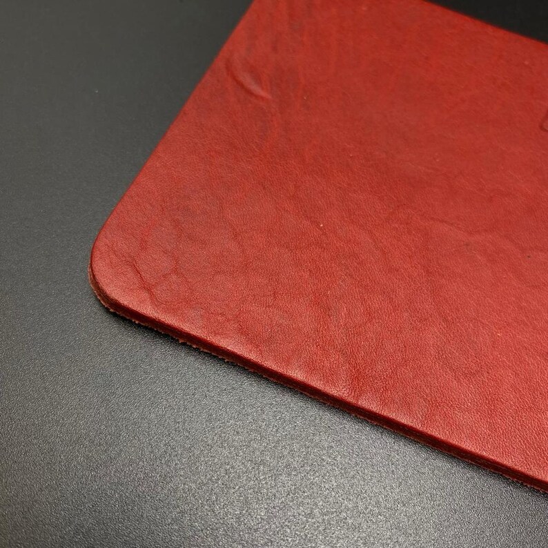 May include: A close-up of a red leather surface. The leather has a textured, grainy appearance.