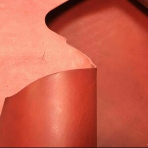 May include: A close-up of a piece of red leather. The leather is folded over, showing the texture and color of the material.