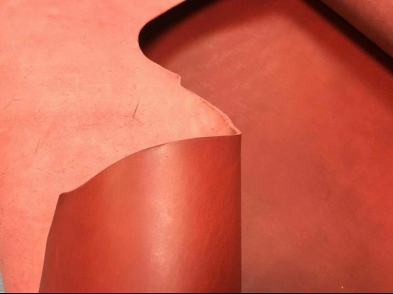 May include: A close-up of a piece of red leather. The leather is folded over, showing the texture and color of the material.