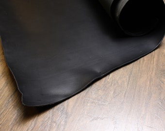 May include: A black leather sheet rolled up on a wooden surface.