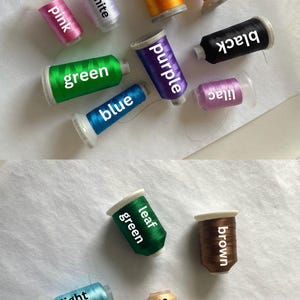 Op de afbeelding: Assortiment van borduurgaren spoelen in verschillende kleuren, waaronder rood, goud, wit, roze, zwart, paars, groen, blauw, lila, bruin, bladgroen, zand en lichtblauw.