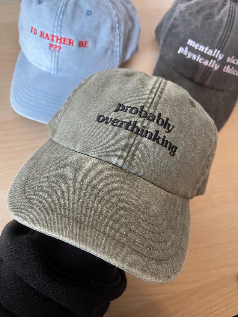 Op de afbeelding: Een groene baseballpet met de tekst "probably overthinking" geborduurd in het zwart op de voorkant.