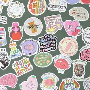 Op de afbeelding: Een verzameling van talloze gestanste vinylstickers met thema's over geestelijke gezondheid, kleurrijke hersenillustraties, bloemmotieven en motiverende teksten zoals Mental Health Matters, Take Your Meds en You Can Do It.