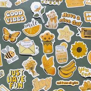 Peut inclure: Une collection d'autocollants sur le thème jaune comprenant diverses illustrations dont un chaton, un chiot, des tournesols, un papillon, une abeille, une banane, un ananas, un pot de miel, une cassette, une machine à écrire et des textes.