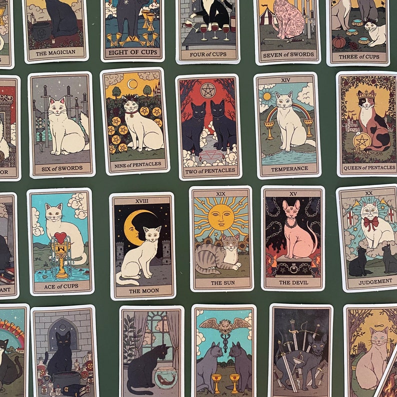 Op de afbeelding: Een set van 22 tarotkaarten met katten in verschillende poses en omgevingen. De kaarten zijn ge&iuml;llustreerd in een vintage stijl met een groene achtergrond. De kaarten omvatten De Magus, Acht van Bekers, Vier van Bekers, Zeven van Zwaarden, Drie van Bekers, Zes van Zwaarden, Negen van Pentakels, Twee van Pentakels, Matigheid, Koningin van Pentakels, Aas van Bekers, De Maan, De Zon, De Duivel, Oordeel.