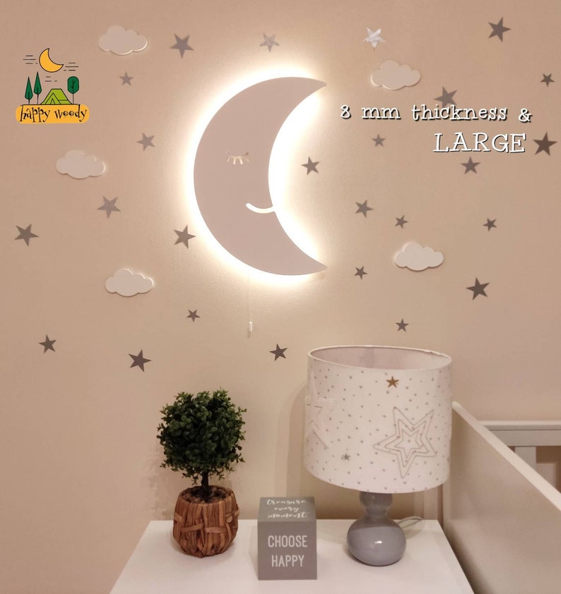 Pu&ograve; includere: Una grande luce notturna a forma di luna crescente bianca con un viso sorridente e gli occhi chiusi. La luce &egrave; montata su una parete con uno sfondo bianco. La parete &egrave; decorata con stelle argentate e nuvole bianche. Il testo "8 mm di spessore & GRANDE" &egrave; scritto in nero sulla parete.