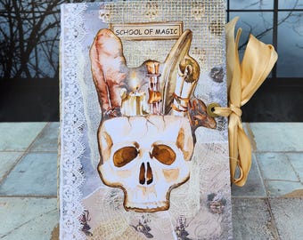 May include: A handmade journal with a skull design and the words "School of Magic" on the cover. The journal is decorated with lace, burlap, and a gold ribbon.