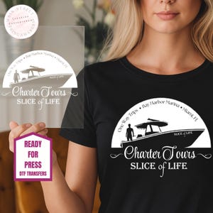 May include: Black t-shirt with a white graphic of a boat and the words "Charter Tours" and "Slice of Life." A clear, rectangular DTF transfer with the same design is held in front of the shirt. The transfer also includes the text "Ready for Press."