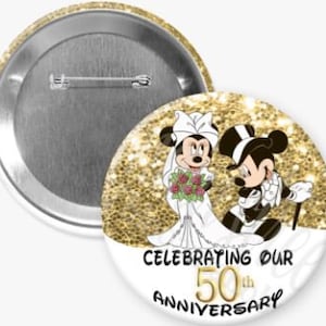 May include: A white button with a gold glitter background featuring Mickey Mouse and Minnie Mouse dressed in wedding attire. The text "Celebrating Our 50th Anniversary" is printed in black and gold.