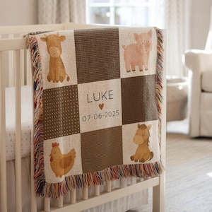 May include: A personalized baby blanket with a farm animal theme. The blanket features a cow, pig, horse, and chicken in a patchwork design. The name "LUKE" and the date "07-06-2025" are displayed in the center. The blanket is draped over a white crib.