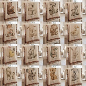 May include: A collection of baby blankets with various animal illustrations, including a bear, zebra, tiger, and monkey, each hugging a baby animal. The blankets are beige with fringed edges and feature the text "LIAM + MOM" and a date.