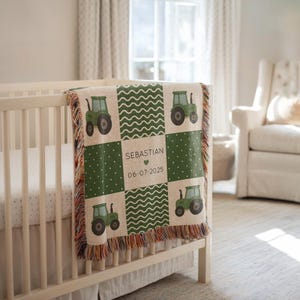 May include: A beige and green baby blanket with a tractor design. The blanket features a patchwork pattern with green tractors, polka dots, and wavy lines. The centre square has the name "Sebastian" and the date "06-07-2025". The blanket is draped over a white cot.