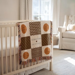 Könnte beinhalten: Eine personalisierte Babydecke mit Basketball-Motiv. Die braune und beige Decke zeigt Basketbälle, Wellenlinien und Tupfen. Der Name "Sebastian" und das Datum "06-07-2025" sind abgebildet. Die Decke liegt über einem weißen Babybett.