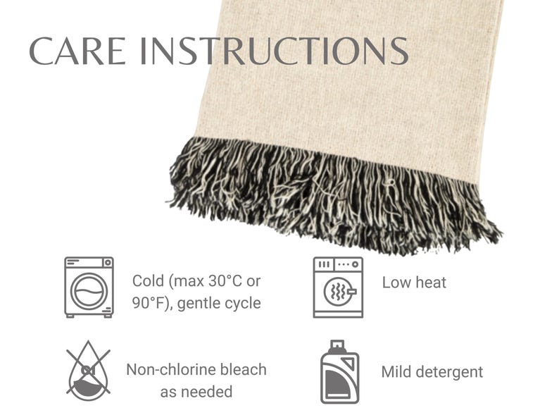 May include: A beige blanket with a black fringe, displaying care instructions. The text reads "CARE INSTRUCTIONS" and includes icons for cold wash (max 90&deg;F), low heat, non-chlorine bleach, and mild detergent.