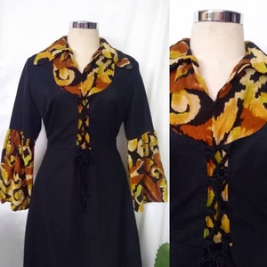 Puede incluir: Un vestido vintage negro con un cordón en la parte delantera y un cuello y mangas con estampado colorido.