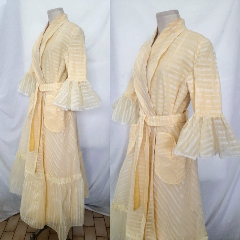 May include: A pale yellow sheer robe with a white stripe pattern and ruffled sleeves. The robe has a sash tie and a patch pocket on the front.