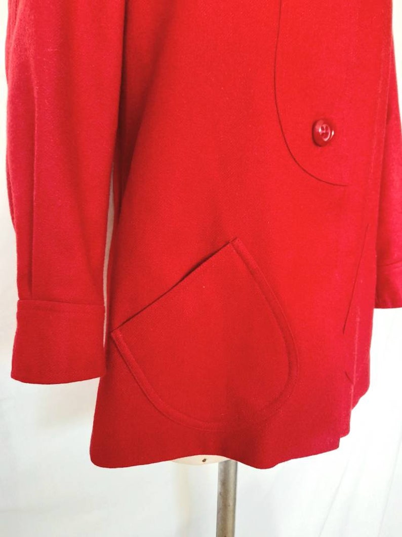 K&ouml;nnte beinhalten: Ein roter Wollmantel mit einem einzigen Knopfverschluss und einer gro&szlig;en aufgesetzten Tasche auf der Vorderseite.