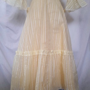 May include: A yellow, sheer dress with a striped pattern and a ruffled hem. The dress has a fitted bodice and a full skirt.