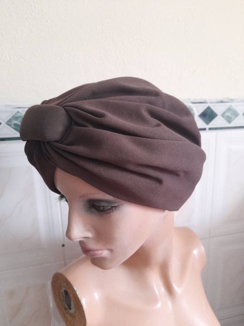 May include: A brown turban style head covering with a knotted detail on top.