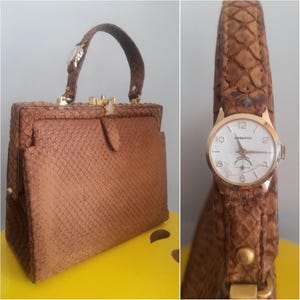 Könnte beinhalten: Eine braune, strukturierte Handtasche mit schlangenlederartigem Muster und einem goldfarbenen Metallrahmenverschluss. Der Griff enthält eine integrierte runde Analoguhr mit weißem Zifferblatt, goldfarbenen Zeigern und dem Schriftzug "DASWATCH".