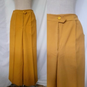 May include: A pair of wide-legged trousers in a mustard yellow colour. The trousers have a zip fly and a button fastening. The fabric is smooth and has a slight sheen.
