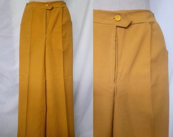 May include: A pair of wide-legged pants in a mustard yellow color. The pants have a zipper fly and a button closure. The fabric is smooth and has a slight sheen.