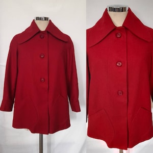 Può includere: Un cappotto vintage in lana rossa con un ampio colletto e chiusura con bottoni. Il cappotto ha due tasche a toppa sul davanti.
