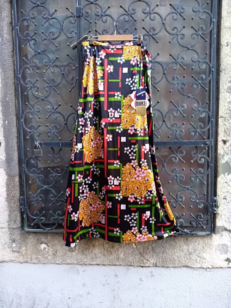 Pode incluir: Uma saia longa preta com estampa geom&eacute;trica e floral colorida. A saia tem um padr&atilde;o verde, vermelho, branco e amarelo. A saia tem uma etiqueta que diz "Duke".