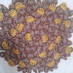 May include: A white silk scarf with a brown and yellow floral design. The design features a large, circular pattern of stylized flowers with yellow centers and brown petals. The scarf has a brown border with the text "ROCHAS PARIS" in white.