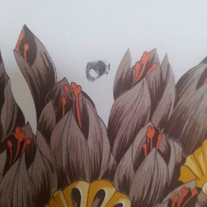May include: A close-up of a fabric with a floral pattern. The fabric features brown, orange, and yellow flowers.