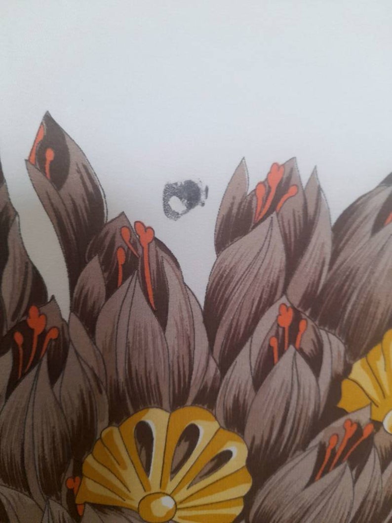 May include: A close-up of a fabric with a floral pattern. The fabric features brown, orange, and yellow flowers.