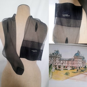 May include: Sheer black stockings displayed on a mannequin. The stockings have a reinforced toe and a band at the top with the text "HIGH FANTASY LOVELY STOCKINGS". A framed watercolor painting of a building is in the background.