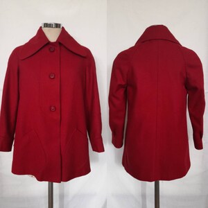 K&ouml;nnte beinhalten: Ein roter Wollmantel mit Kragen und vier Kn&ouml;pfen vorne. Der Mantel hat zwei Taschen vorne und lange &Auml;rmel.