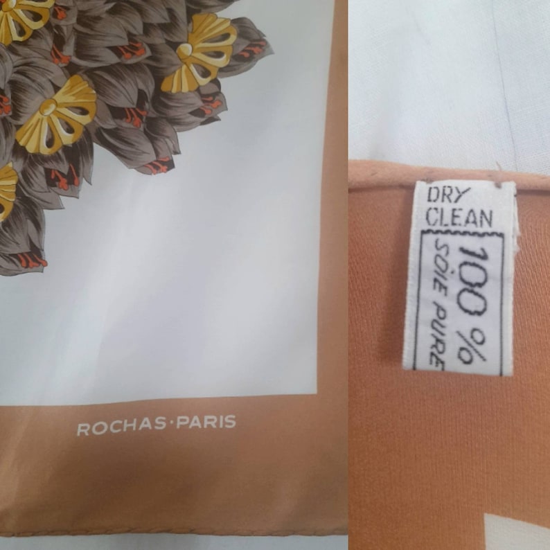 May include: A white silk scarf with a brown and gold floral design. The scarf has a brown border and the text "ROCHAS-PARIS" printed on the bottom. The care label indicates that the scarf is 100% silk and should be dry cleaned.